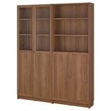 Bibliothèque en bois BILLY avec plusieurs étagères, certaines fermées par des portes et d’autres ouvertes, dans une finition brune.