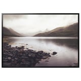 Cadre photo BJÖRKSTA : grand cadre rectangulaire en aluminium noir avec un imprimé de paysage montagneux à l’intérieur, avec un rivage rocheux et une eau calme.