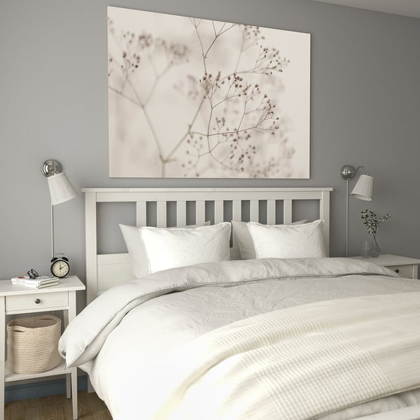 Chambre moderne avec lit BJÖRKSTA, murs gris, toile florale, literie blanche, tables de chevet, réveil, panier.