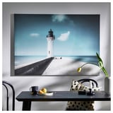 Photo de phare blanc sur le mur avec table : tasse, orange, tulipe, chaise, lampe.