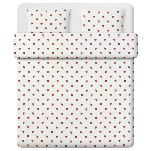 Cette image montre un lit avec une housse de couette blanche ornée de petits motifs de cœurs rouges. La matière est un mélange de coton recyclé et de viscose.