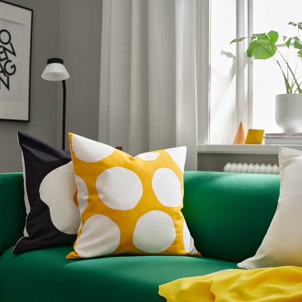 Coussin à pois jaunes sur canapé vert, pièce éclairante. Coton, 16 carrés, avec des accessoires noirs, blancs et jaunes.