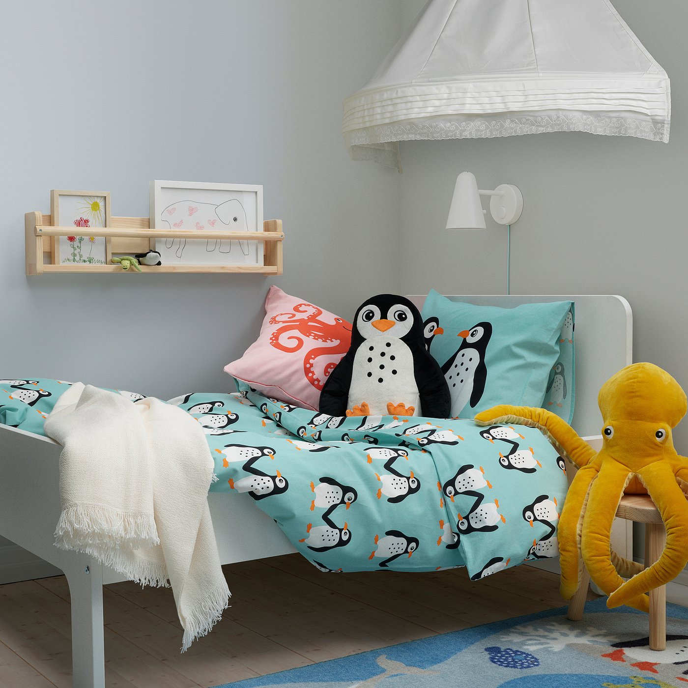 Lit douillet pour enfants sur le thème des pingouins bleus. Coussins décoratifs, peluches et étagère murale avec art. Points forts de la literie Blåvningad.