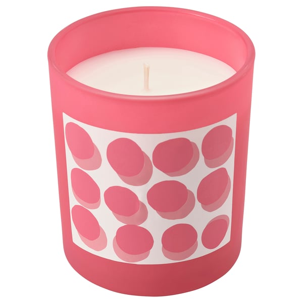 Une bougie parfumée rouge nommée BLODBOK. Il a une tasse en verre avec un motif ludique de points rouges. Le design est simple et accueillant.