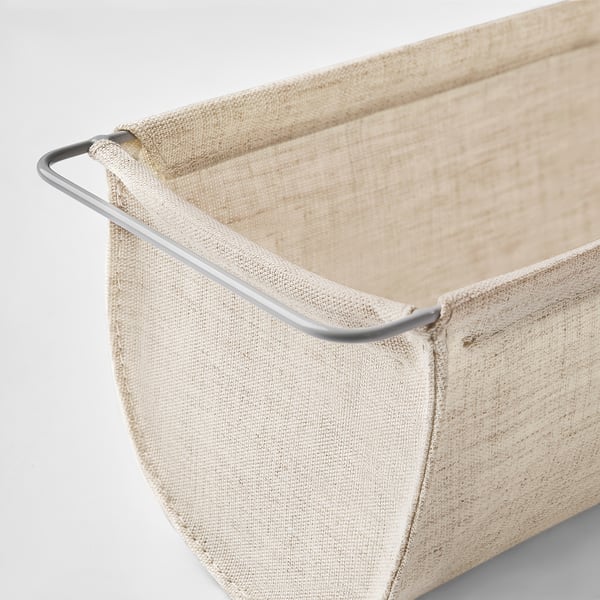 Gros plan de la corbeille de stockage BOLLÖSUND beige avec poignée métallique robuste.