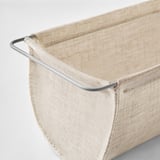 Gros plan de la corbeille de stockage BOLLÖSUND beige avec poignée métallique robuste.