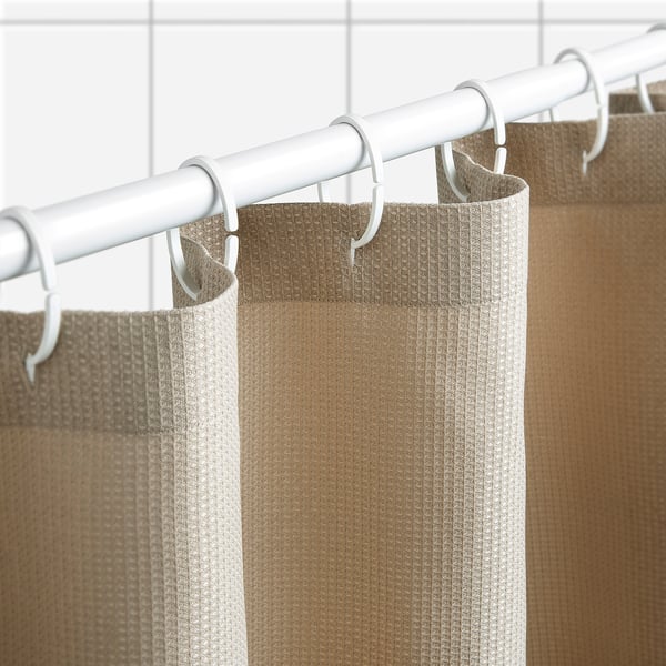 Le rideau de douche de couleur neutre avec texture gaufrée est suspendu à une tige blanche et à des crochets, repousse l’eau.