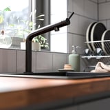 Le robinet de cuisine BOSJÖN noir aux courbes douces et à la finition élégante en acier inoxydable se distingue dans les ustensiles de cuisine.