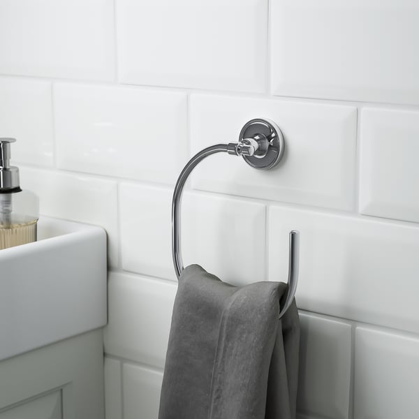 Anneau porte-serviettes chromé sur mur carrelé, tenant une serviette grise, faisant partie des accessoires de salle de bain BROFJÄRDEN.