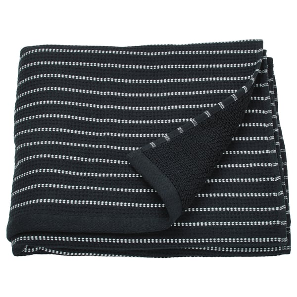 La serviette BROKGINST est noire avec des rayures blanches, en coton, rectangulaire et pliée avec une texture gaufrée visible.