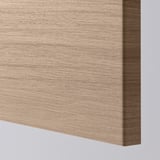 Gros plan de la façade d’une armoire de cuisine en bois lisse avec une texture à grain fin. Détail des bords visible.