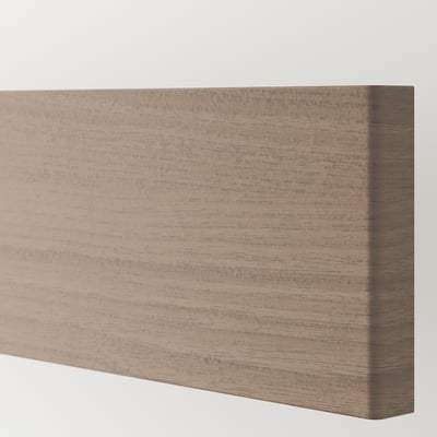 Un gros plan de la façade d’une armoire de cuisine BROKHULT, mettant en valeur sa surface lisse texturée en noyer et son design élégant.