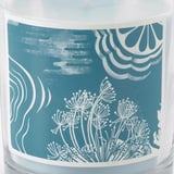 Pot de bougie étiqueté bleu avec des motifs floraux et vagues blancs.
