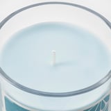 Bougie circulaire en verre avec cire teintée bleutée, mèche centrale, bord poli.