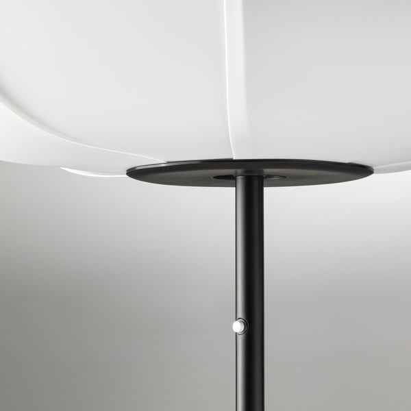 Lampadaire moderne avec support noir élégant, supportant un abat-jour rond et blanc. Émet une lumière douce et diffuse.