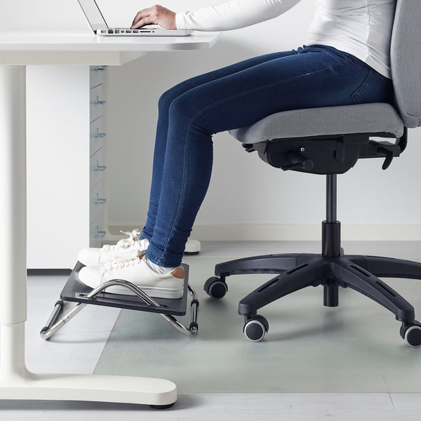 Personne utilisant le repose-pieds DAGOTTO sous le bureau, ajustant avec le pied pour plus de confort.