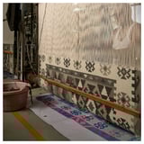 Tapis tissé à la main avec des motifs géométriques gris sur métier à tisser. Mélange de laine et de coton, bords frangés. Fabrication traditionnelle, design moderne.