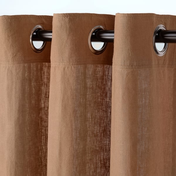 Rideaux beiges avec œillets à œillets. Les rideaux sont dotés d’un drapé doux, laissant passer la lumière et l’air, offrant ainsi de l’intimité.