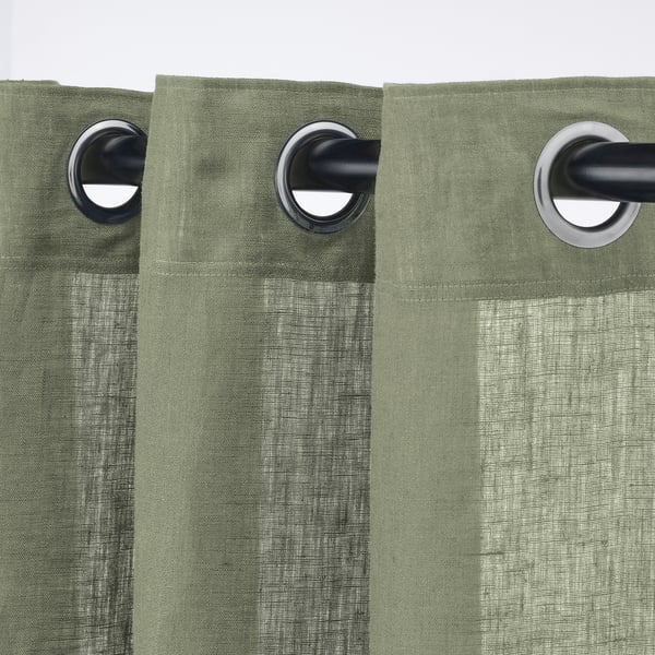 Des rideaux verts avec œillets pendent sur une tige noire, montrant un design ouvert.