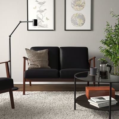 Canapé EKENÄSET noir avec grain de bois dans un salon moderne.