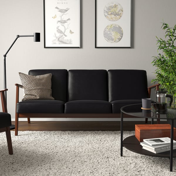 Canapé noir moderne, tapis en laine, table basse et art mural dans un salon confortable.