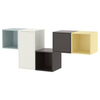 Quatre étagères en forme de cube en bleu, blanc, gris et jaune, montées sur un mur, présentant une solution de rangement moderne.