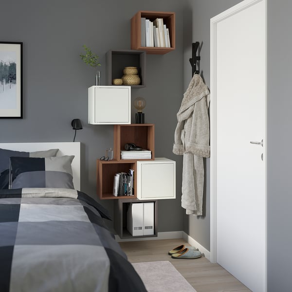 Chambre moderne avec étagères EKET, mêlant rangements ouverts et fermés, haut sur le mur. Des draps gris complètent le look minimaliste.