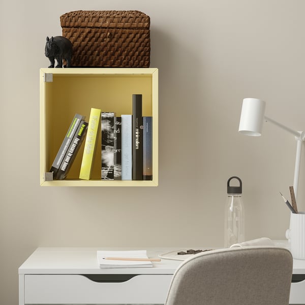 Étagère EKET jaune avec livres, panier, décor de cheval, à côté du bureau avec chaise, lampe, porte-stylo.