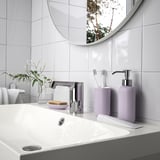Évier blanc avec robinet chromé, miroir rond, savon à la lavande, série EKOLN et plante.