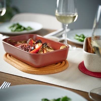 Configuration du dîner avec support en bambou, plat, légumes, verre et assiettes.