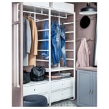 Une armoire blanche ELVARLI avec étagères et tiroirs. Il permet de ranger des jeans, des manteaux et des sacs. Une lampe et un miroir se trouvent à proximité.