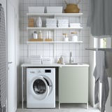 Coin buanderie moderne : unité ENHET blanche avec évier, étagères et machine à laver. Armoire gris-vert, serviettes empilées, design épuré.