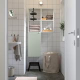 Salle de bain moderne avec meuble de rangement gris-vert clair ENHET, compartiments ouverts/fermés, installation sous étagères.
