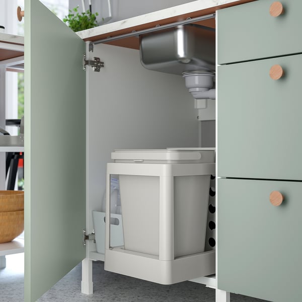 Une armoire murale gris-vert avec deux étagères, permettant de ranger des articles de cuisine tels que des bouteilles et des bocaux, offrant un rangement organisé et élégant.