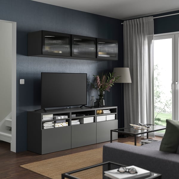 Salon moderne avec des murs gris foncé, une télévision à écran plat et un centre de divertissement en verre roseau.