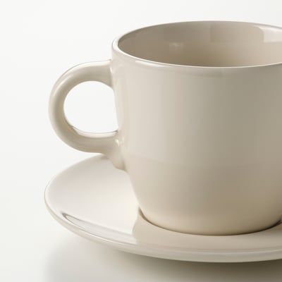 Quatre tasses et soucoupes blanches sont disposées en rangée. Les bonnets ont un design rond simple et une finition brillante.