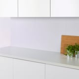 Cuisine moderne avec armoires blanches. Planche à découper, plantes et panneau FAGERFORS.