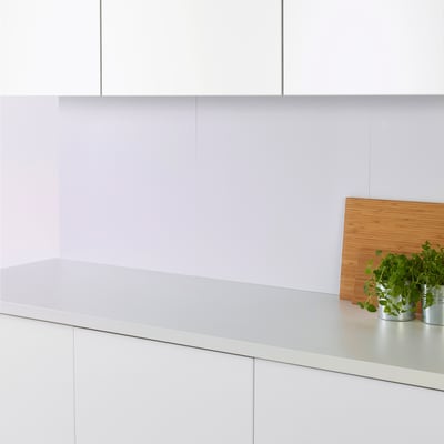 Cuisine moderne avec armoires blanches. Planche à découper, plantes et panneau FAGERFORS.