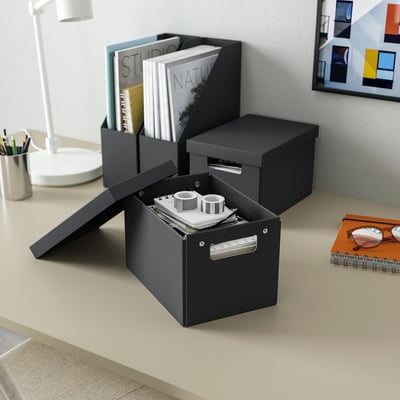 Trois boîtes FJÄDERHARV sur le bureau : l’une ouverte avec des conteneurs, les deux fermées avec des papiers, des poignées argentées.