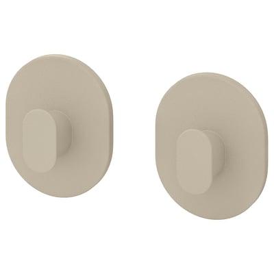 Deux crochets muraux circulaires beiges avec évidements rectangulaires. Design simple et moderne, idéal pour suspendre des objets.