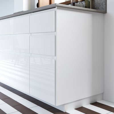 Des placards de cuisine modernes blancs avec une finition brillante, des lignes droites, plusieurs tiroirs, des poignées élégantes et un design minimaliste.