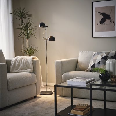 Un lampadaire FOLKBÅT noir moderne avec deux lumières réglables en forme de dôme sur un grand support, offrant un éclairage polyvalent.