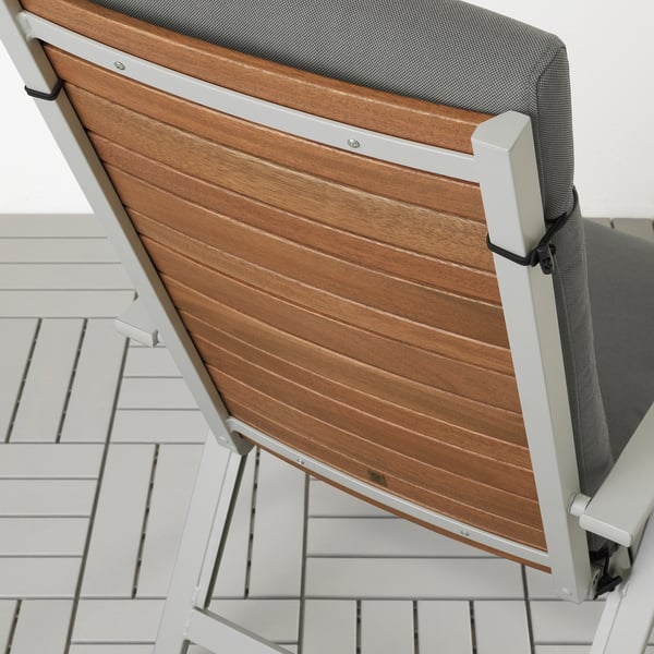 Coussin d’extérieur avec chaise à lattes en bois, montrant une fonction de fixation de la sangle élastique.