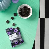 Ouvrez les bonbons à la réglisse FYRTAKT d’IKEA sur la table. Sachet étiqueté réglisse douce, bonbons renversés et dans un bol.