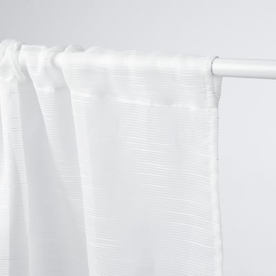 Rideau transparent blanc suspendu, permettant la lumière tout en assurant l’intimité.