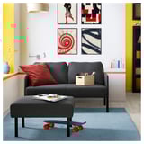 Salon moderne avec canapé GLOSTAD gris et pouf. Coussins colorés, art, vase bleu et décor de planche à roulettes.