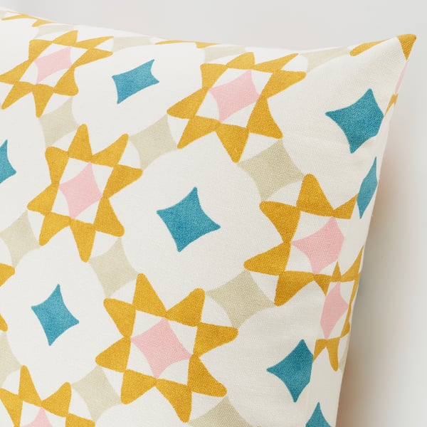Étoiles géométriques colorées sur coussin blanc. Coton doux, design frais.