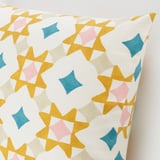 Étoiles géométriques colorées sur coussin blanc. Coton doux, design frais.
