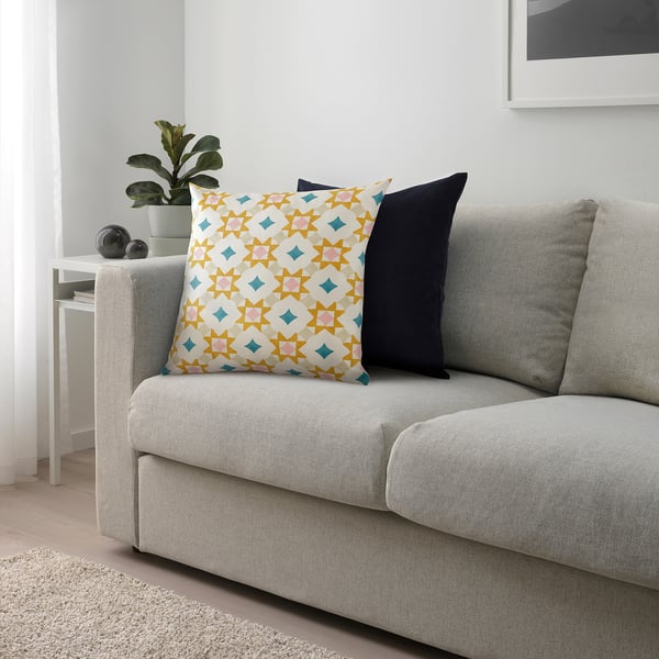Coussin GOKVÄLLÅ sur canapé à motifs géométriques, près de la table de plante.