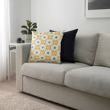 Coussin GOKVÄLLÅ sur canapé à motifs géométriques, près de la table de plante.
